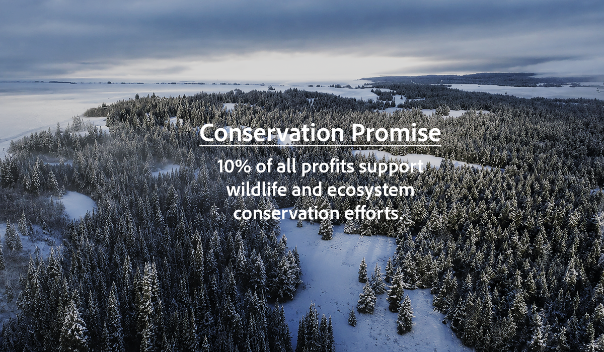 Aerial view of a snowy forest and frozen water under a cloudy sky, with overlaid text reading 'Conservation Promise' and '10% of all profits support wildlife and ecosystem conservation efforts.'.